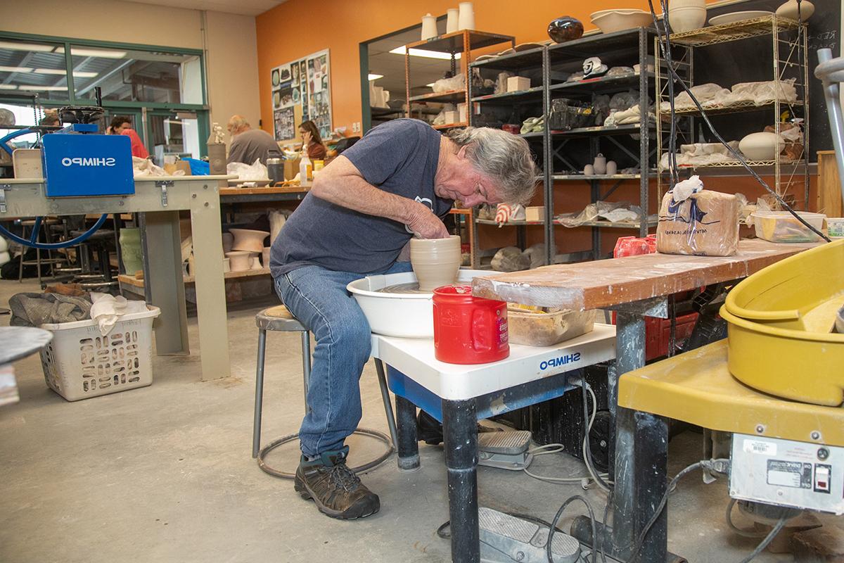 Man using pottery throwing wheel.