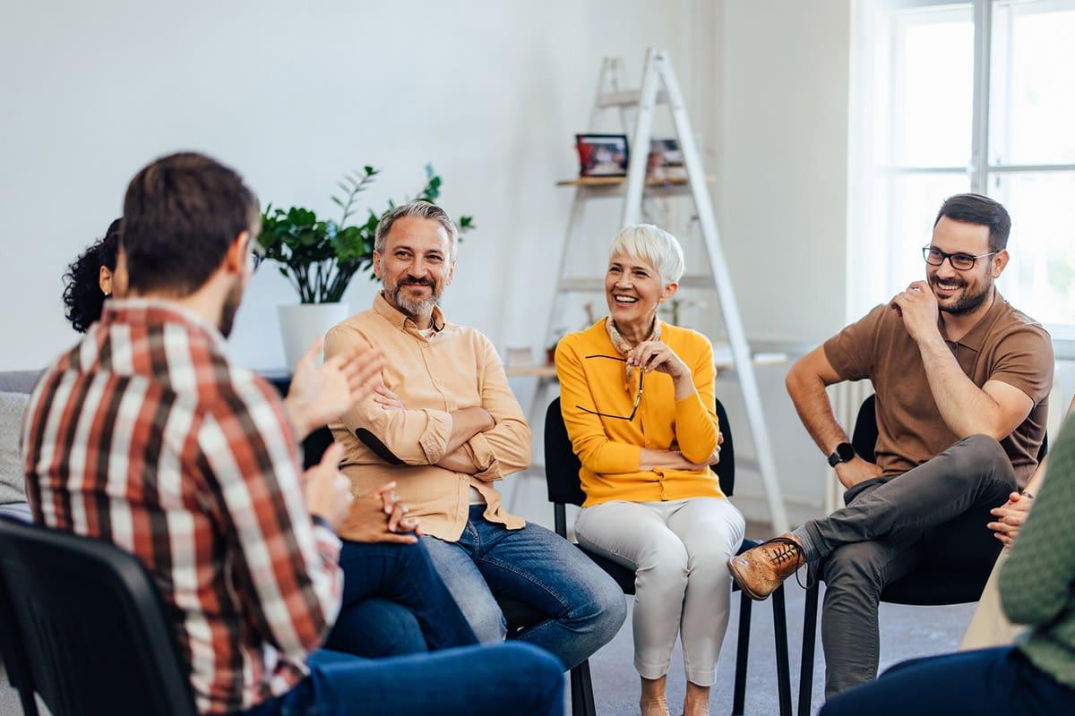 A therapist leading a group counseling session with a diverse group of people sitting in a circle