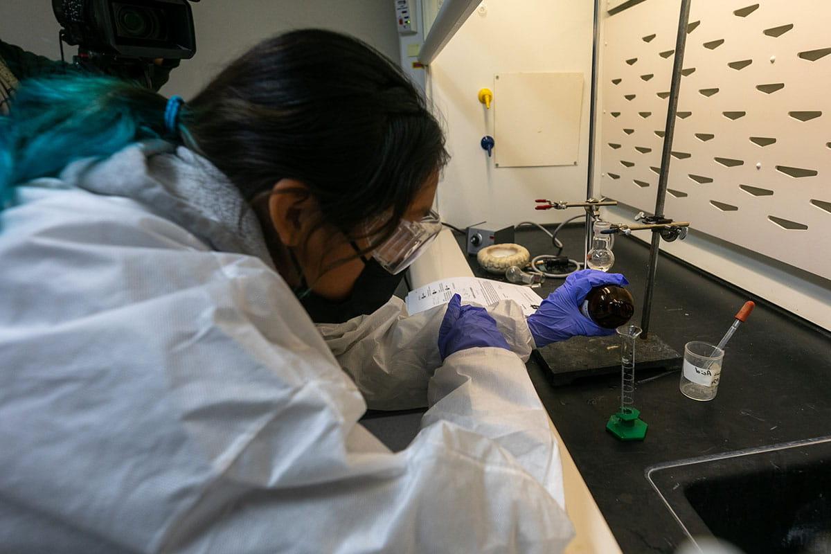 A San Juan College student pouring a liquid into a test tube in a chemistry lab